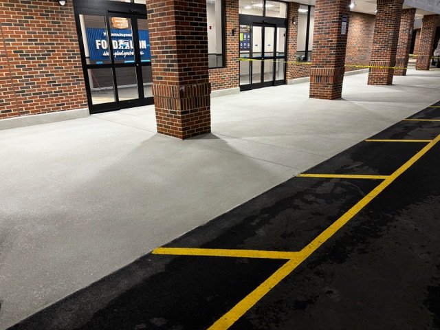 Freshly coated concrete walkway at a retail storefront